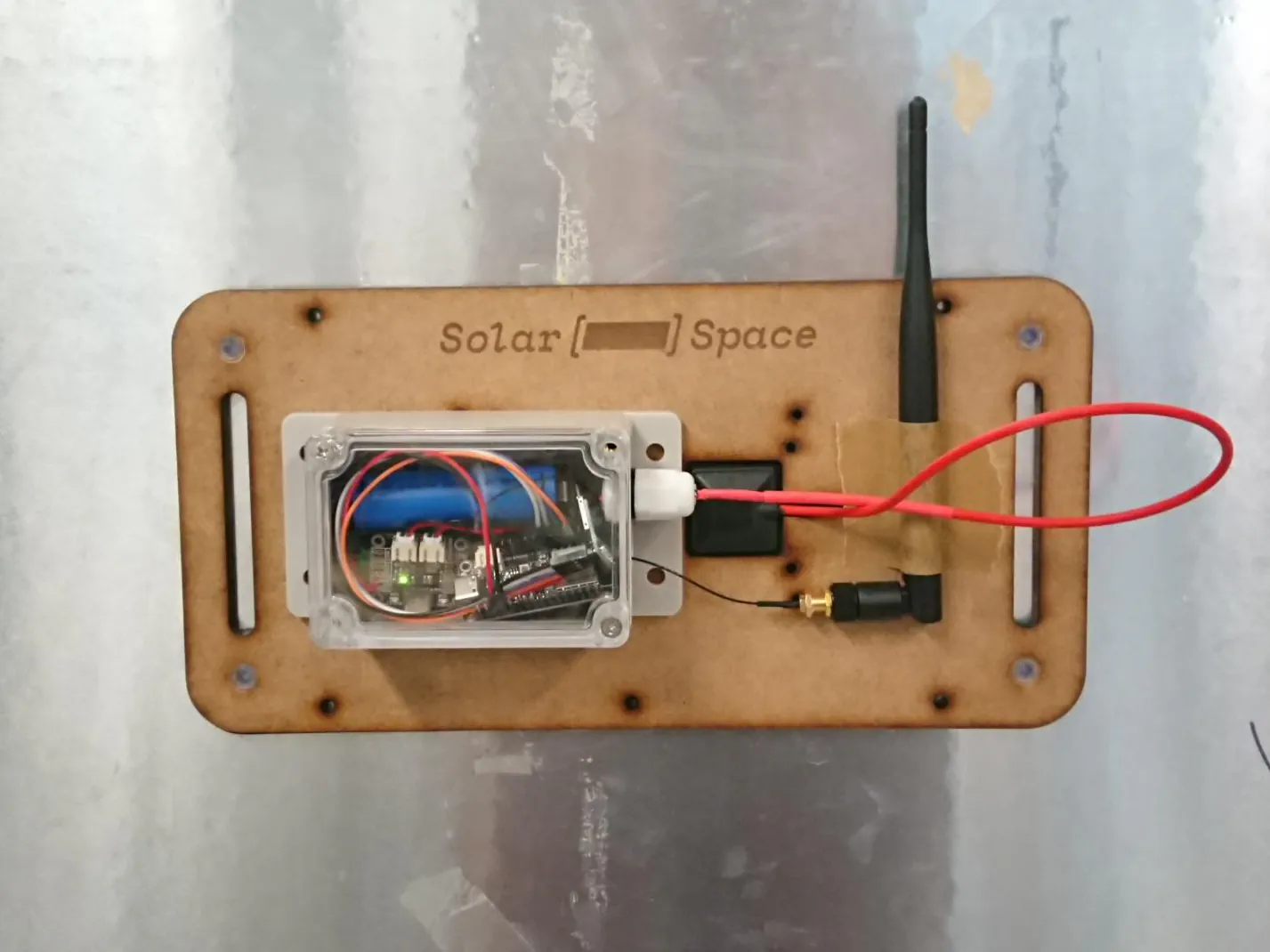 The initial prototype, components are crammed into an off-the-shelf box, the antenna in taped on and the frame shows various attempts at placements.